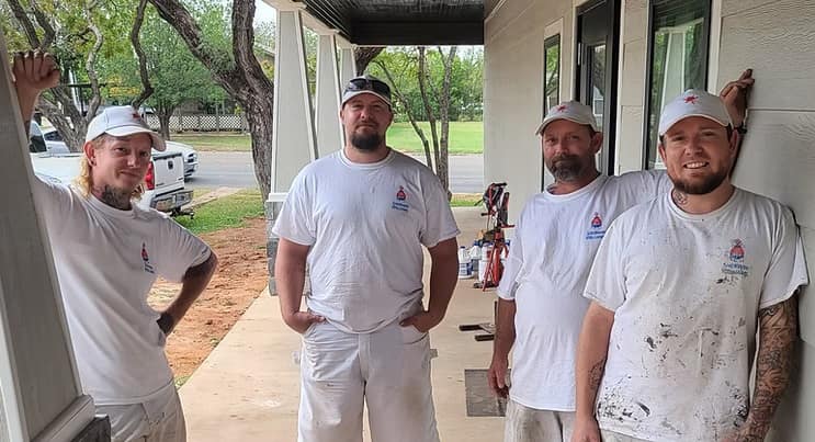 The Covenant Coatings 323 crew in white work shirts standing on the porch of a freshly painted home